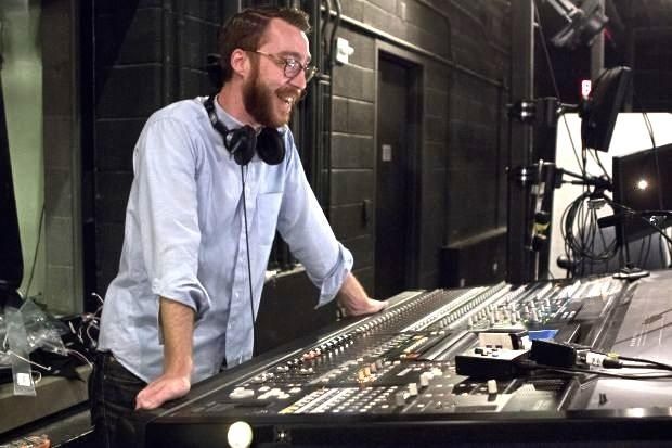 Sound engineer wearing headphones at a large audio mixing console