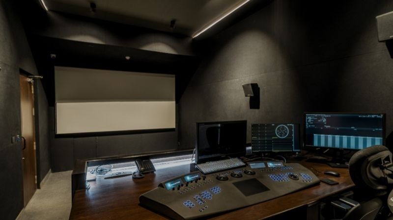 Dark color grading suite with control panel and multiple monitors